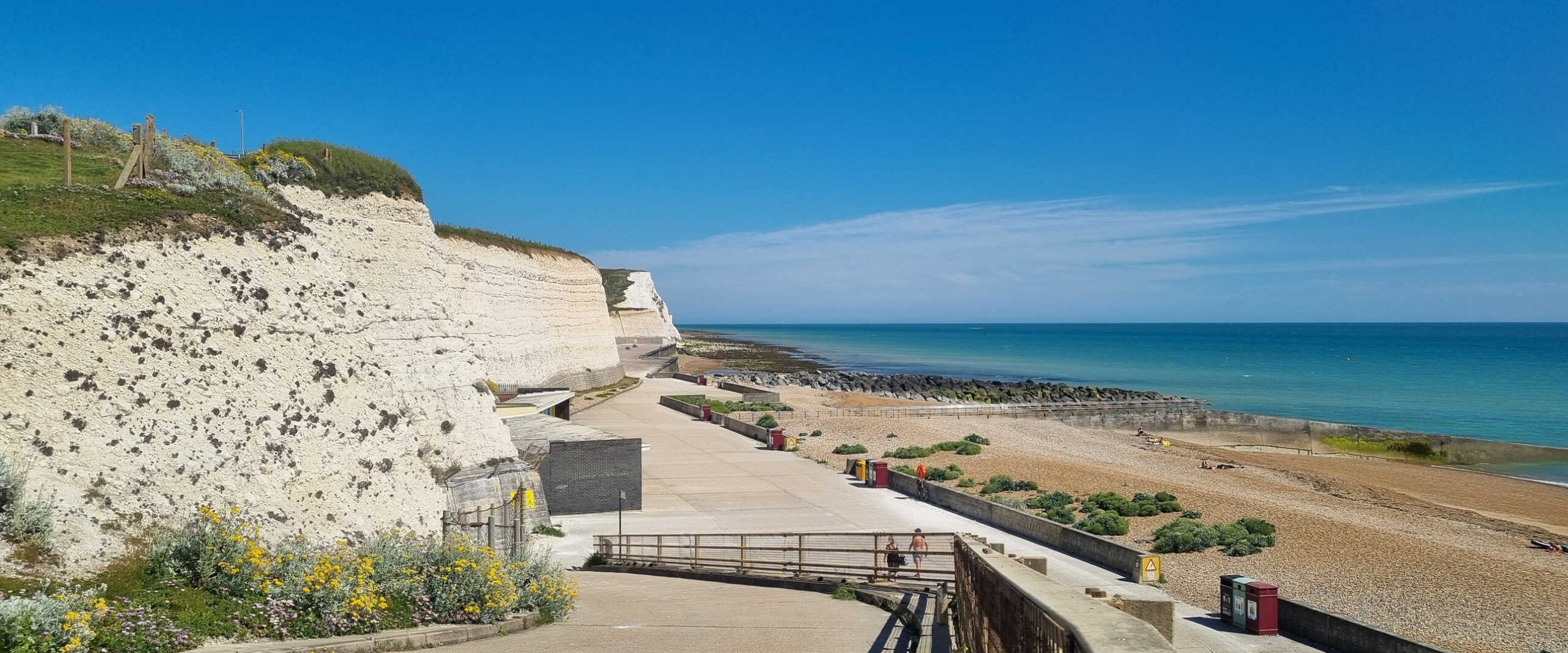 The white chalk cliffs, promenade and shingle beach on the undercliff walk at Saltdean on a sunny day.